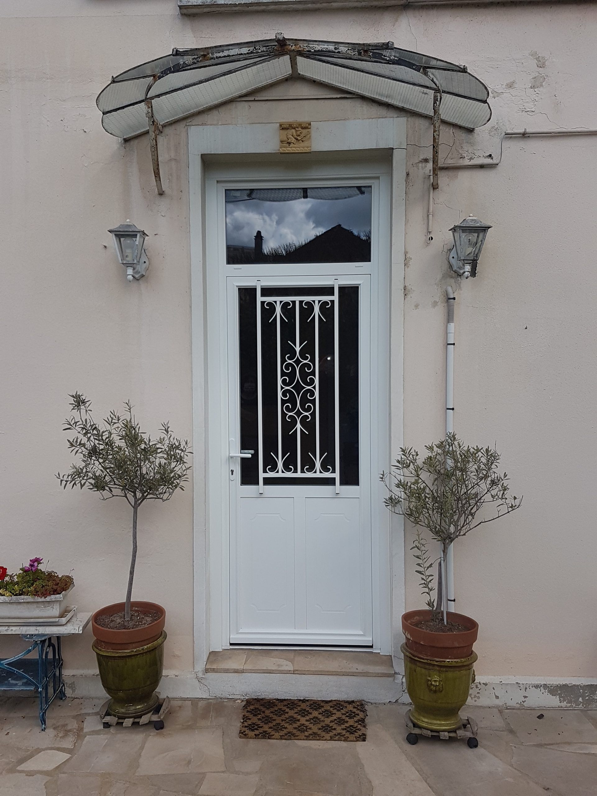 Porte d’entrée blanche avec imposte et grille