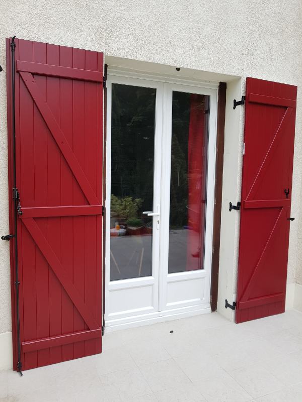Volets battants rouges installés sur une maison